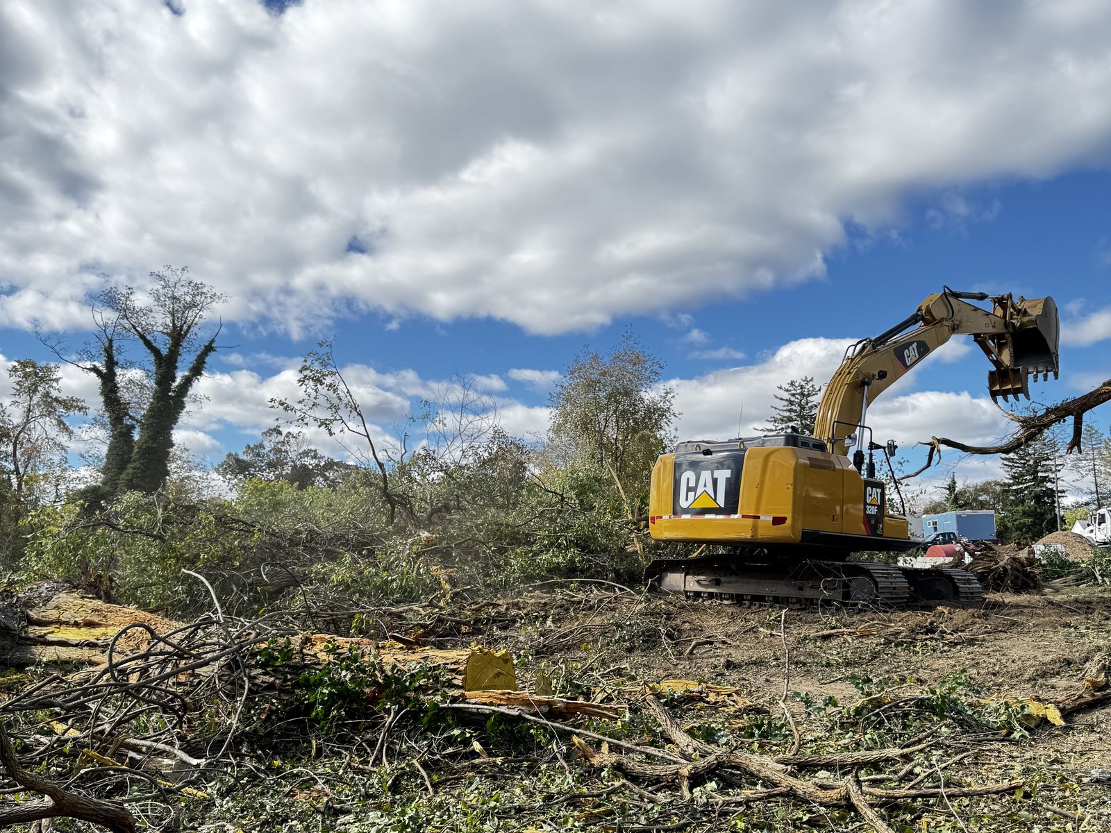 Excavator clearing brush and felled timber on a cleared lot