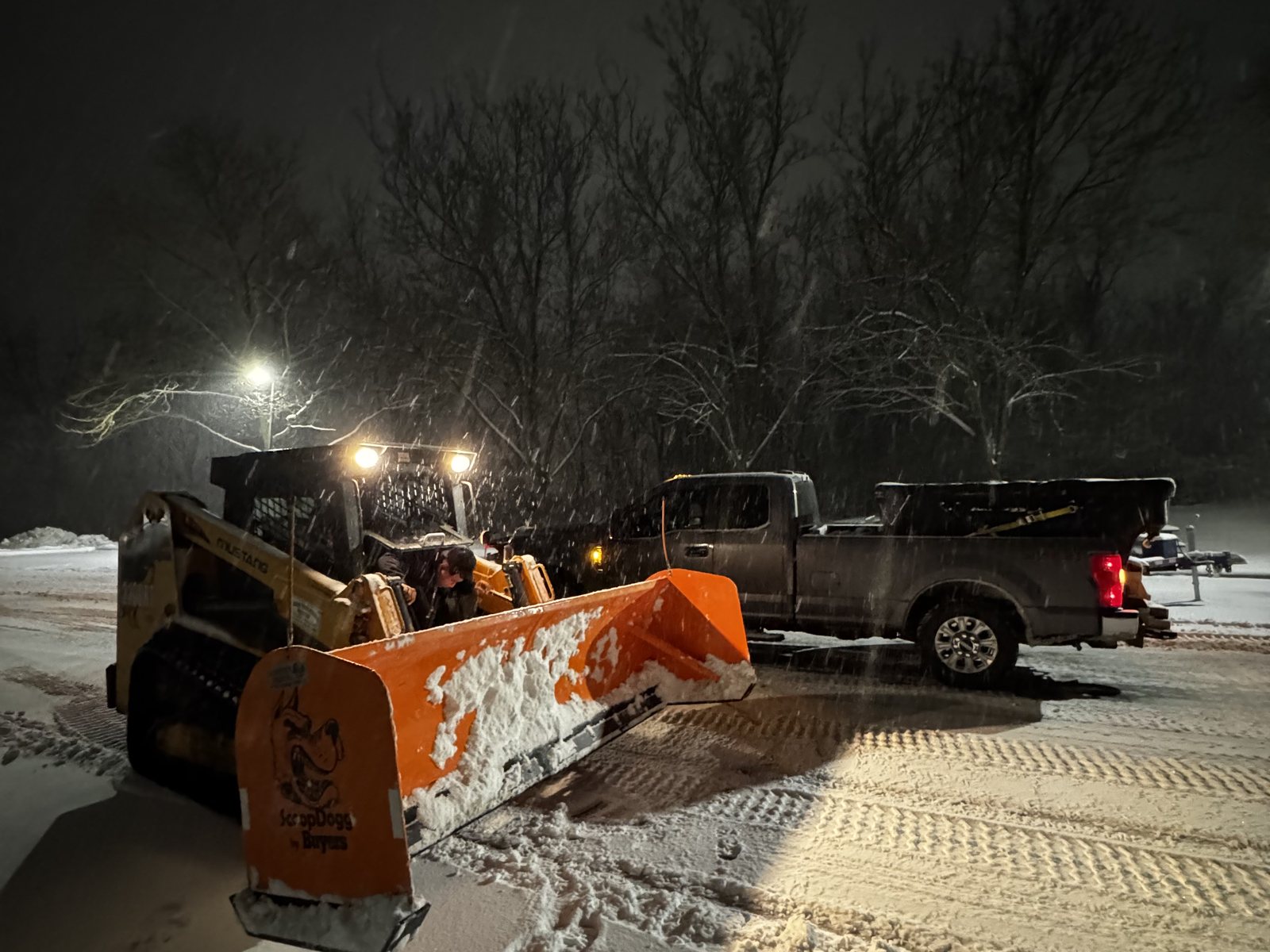 Overnight snow removal — loader pusher and plow trucks clearing a commercial lot after hours